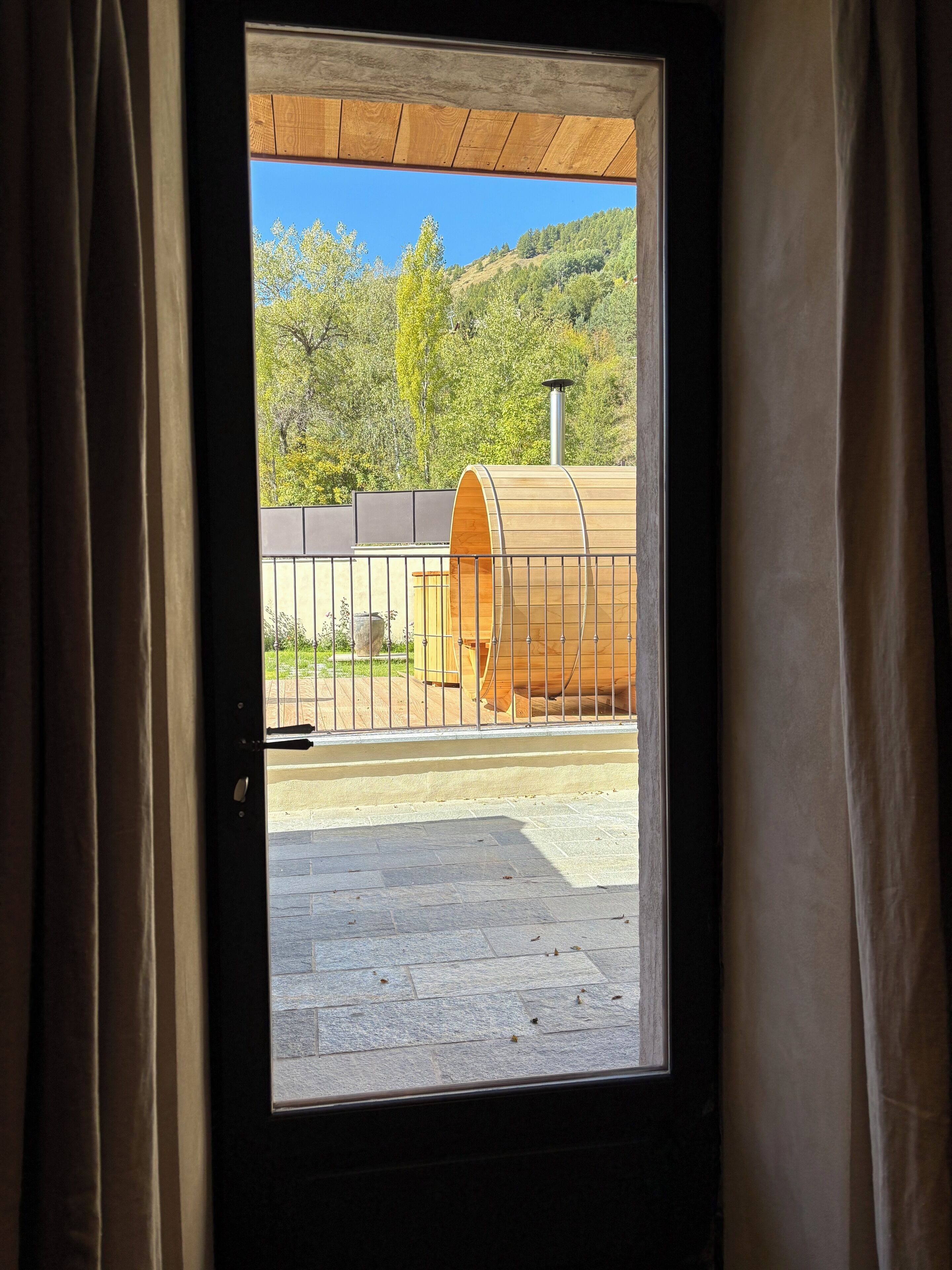 Blick durch ein Fenster auf ein Gebäude mit einer Holzfässern-Struktur davor.