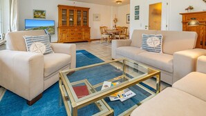 Un salon avec deux canapés beige, une table basse en verre et un meuble en bois.