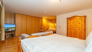 A bedroom with a large bed, wooden wardrobe, and a television on a wooden cabinet. - Rüm hart - Spacious vacation apartment Rüm hart on Sylt with terrace for max. 5 persons. (Sylt-Ost)
