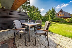 An outdoor patio with a table and four chairs, a bottle of wine, and a menu on the table.