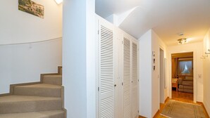 A staircase leading to a room with a bed, a window with curtains, and a small seating area. - Rüm hart - Spacious vacation apartment Rüm hart on Sylt with terrace for max. 5 persons. (Sylt-Ost)