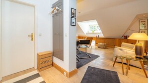 A modern apartment with a loft-style living area, a glass door, a wooden floor, and a cozy seating arrangement. - Goofys Will - Modern vacation apartment Goofys Will on Sylt with comfort and (Sylt)