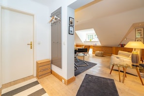 Un appartement moderne doté d’un espace de vie aménagé dans un style « loft », d’une porte en verre, d’un plancher en bois et d’un coin salon confortable.