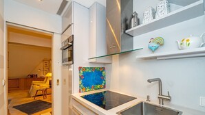 A modern kitchen with a built-in stove, a stainless steel sink, and a glass shelf above the counter. - Goofys Will - Modern vacation apartment Goofys Will on Sylt with comfort and (Sylt)