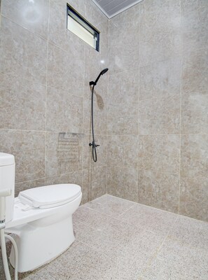 A bathroom with a toilet, a shower, and a tiled floor.