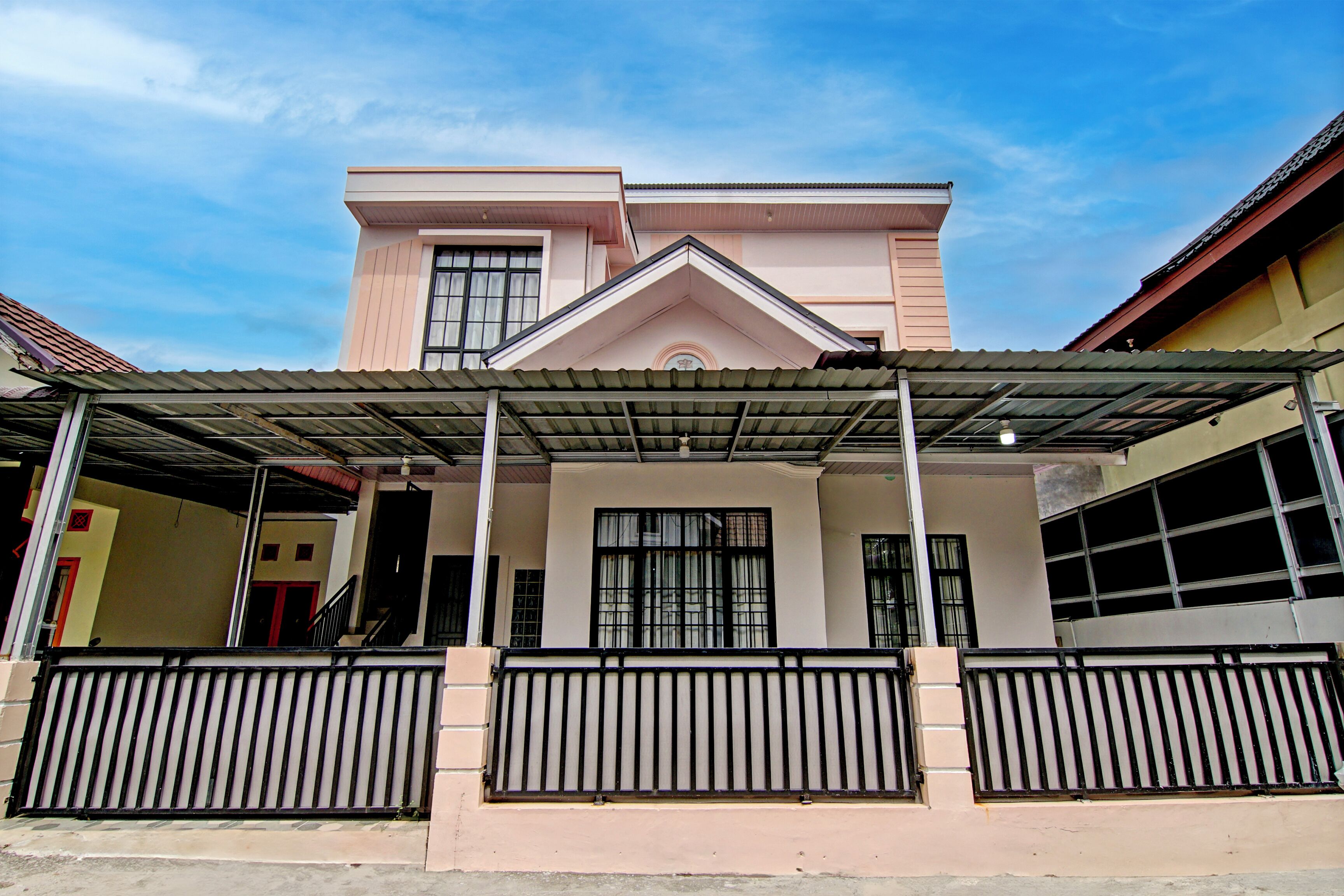 A two-story building with a covered entrance and a gated driveway.