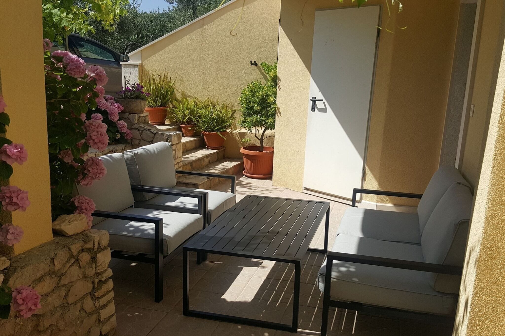 Un patio al aire libre con un sofá, una mesa y plantas en macetas.