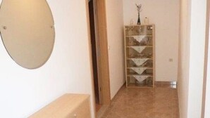 A hallway with a tiled floor, a wall-mounted mirror, and a storage unit with multiple compartments.