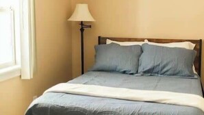 Un llit amb estructura de fusta, una làmpada i una finestra.