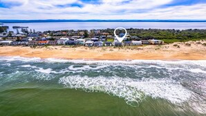 A coastal residential area with houses along the beachfront, a sandy beach, and the ocean. - Time and Tides - Beachfront, Stunning Ocean Views. (THE ENTRANCE NORTH)
