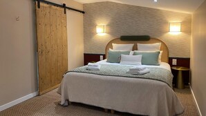 A neatly made bed with a wooden headboard, a sliding door, and two wall-mounted lights. - Beautiful villa with indoor pool (Sainte-Cécile)