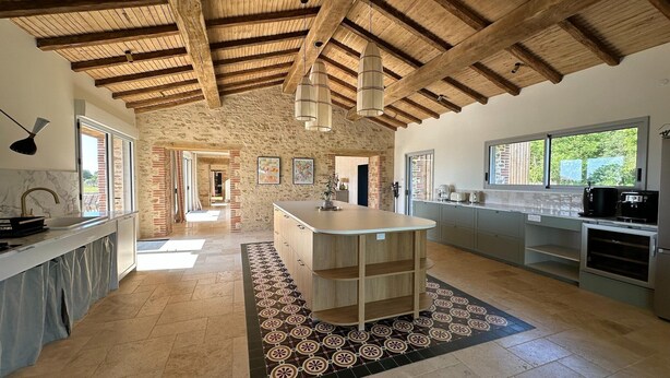 A spacious kitchen with a central island, exposed wooden beams, and a view to the outside. - Beautiful villa with indoor pool (Sainte-Cécile)