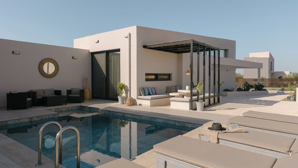Un espace piscine extérieur moderne, doté de chaises longues, d’un coin salon et d’une pergola.