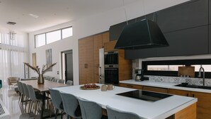 Une cuisine moderne dotée d’un grand îlot central, de meubles en bois et d’un luminaire noir suspendu au plafond.