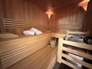 A wooden sauna with benches, towels, and a bucket.