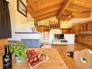 Eine gemĂŒtliche KĂŒche mit Holzbalken, ein Essbereich mit gedecktem Tisch und eine Treppe, die zu einer oberen Ebene fĂŒhrt.