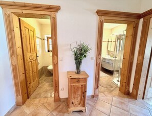 Ein Korridor mit HolztĂŒren, die zu einem Badezimmer und einer Dusche fĂŒhren.