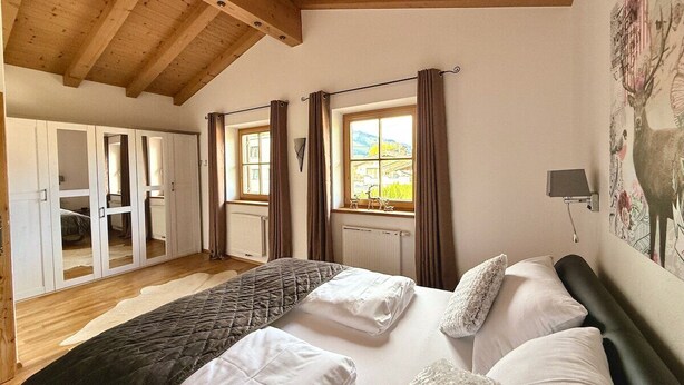 Um quarto com uma cama grande, um guarda-roupa e uma janela com cortinas.