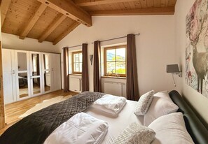 A bedroom with a large bed, a wardrobe, and a window with curtains.