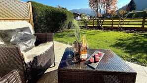 Um pátio com móveis de vime, uma garrafa de vinho e um copo.