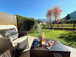 Eine Terrasse mit Korbmöbeln, einer Weinflasche und einem Glas.