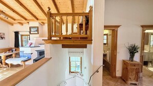 Uma escada de madeira com vista para uma sala de estar e cozinha.