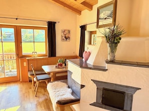 A cozy room with a fireplace, wooden furniture, a bench, and a window with curtains.