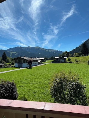 A rural setting with a house, a clear sky, and mountains in the background.