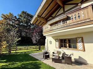 A two-story building with a balcony, outdoor seating area, and a well-maintained lawn.
