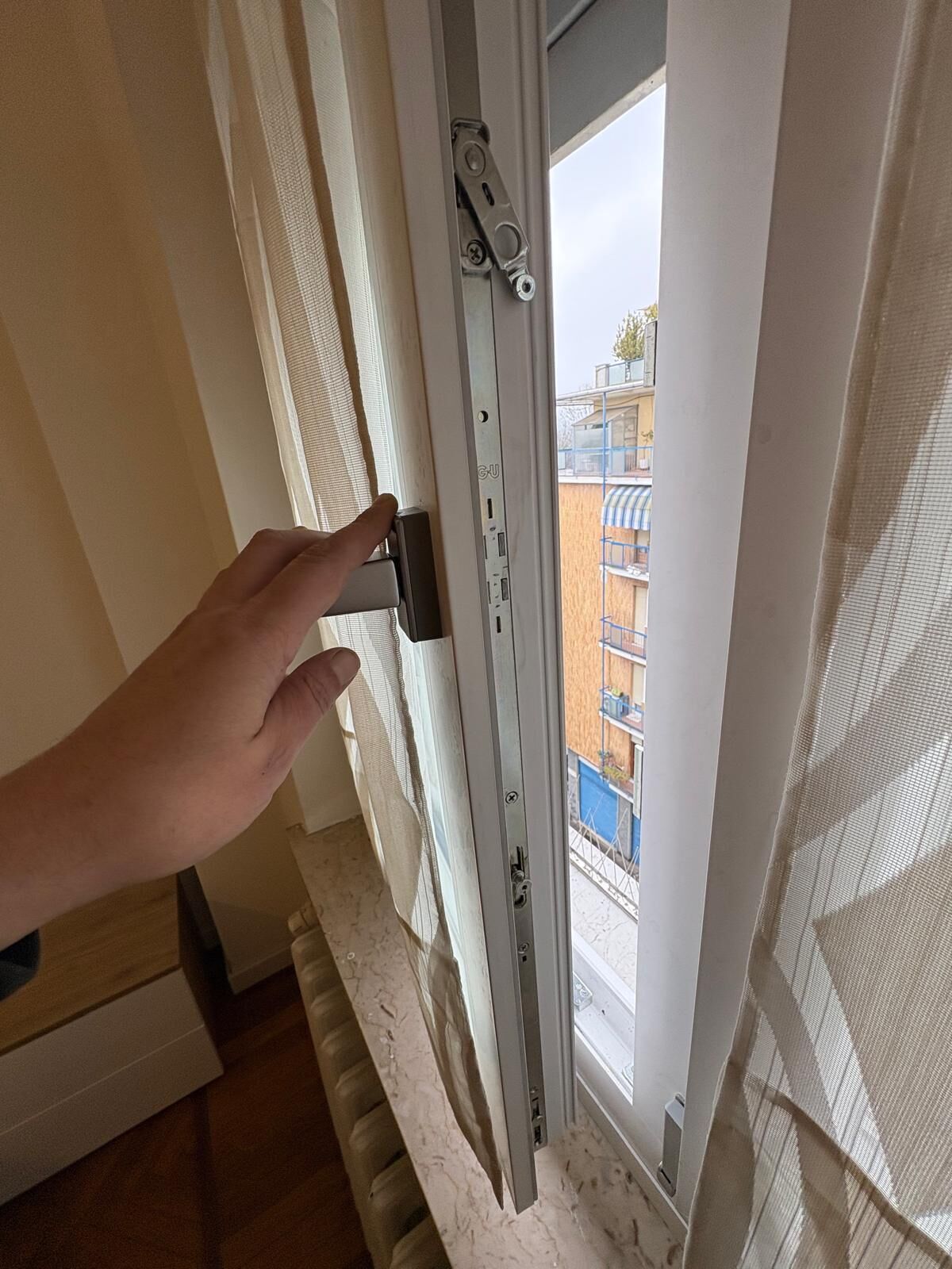 A hand operating a window latch mechanism.