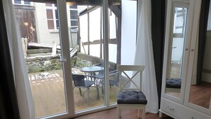 A room with a sliding glass door leading to an outdoor patio with a table and chairs. - Apartment 'Homberger Altstadt' with private terrace and Wi-Fi (Homberg (Efze))