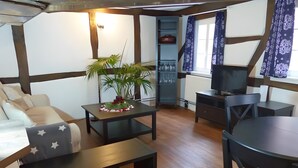 A cozy living room with a sofa, a coffee table, a TV, and a plant. - Apartment 'Homberger Altstadt' with private terrace and Wi-Fi (Homberg (Efze))