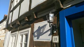Eine Gebäudefassade mit blauer Tür, der Hausnummer 20 und einem traditionellen Fenster mit Fensterläden.