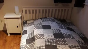 A bedroom with a white bed, a nightstand with a lamp, and a window with curtains. - Apartment 'Pilgerzimmer' with Wi-Fi (Homberg (Efze))