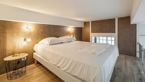 Ein modernes Schlafzimmer mit einem großen Bett, Nachttischlampen und Blick ins Freie.