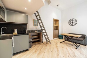 A modern kitchen with grey cabinets, a wooden countertop, and a ladder leaning against the wall.