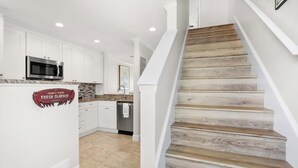 A kitchen with white cabinets, a stainless steel microwave, and a sign for Crabby's Kitchen. - Oceanfront, Pool, Tennis, BBQ, Patio, Free Parking (St. Augustine)