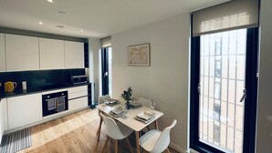 A modern kitchen with white cabinets, a black countertop, and a dining area with a white table and chairs.