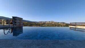 A swimming pool with a stone structure and a view of mountains. - Bellevia Stone Pool Villa (Nea Styra)
