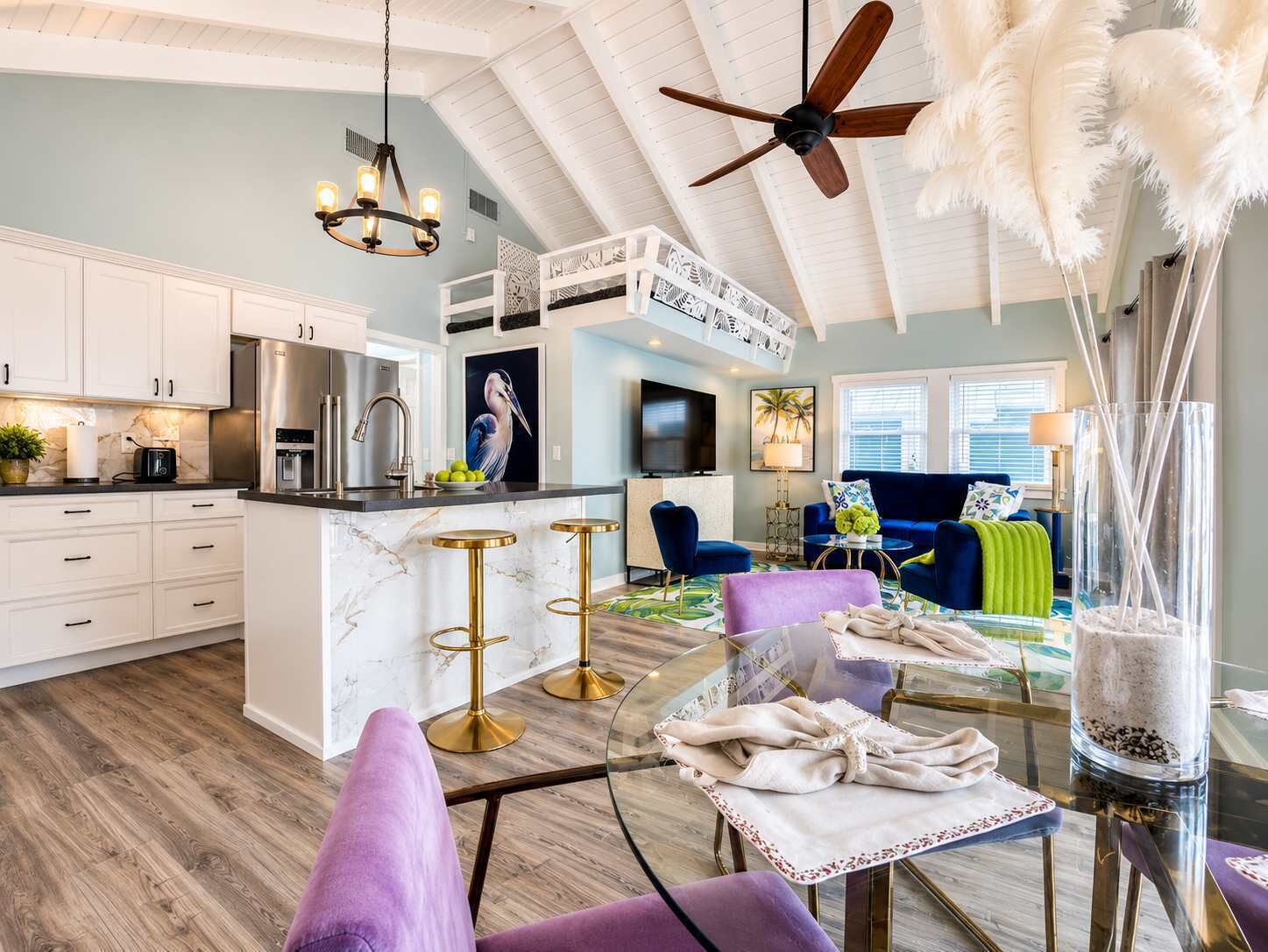 A modern kitchen with white cabinets, a marble island, and gold bar stools.