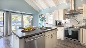 Una cocina moderna con una isla central, electrodomésticos de acero inoxidable y vistas al exterior.