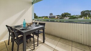 A balcony with a table set for two, a blue bottle, and a basket.