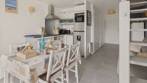 A modern kitchen with white cabinetry, a dining table with chairs, and a staircase leading to an upper level.