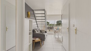 A modern interior with a sofa, a small table, and a ladder leading to a balcony.