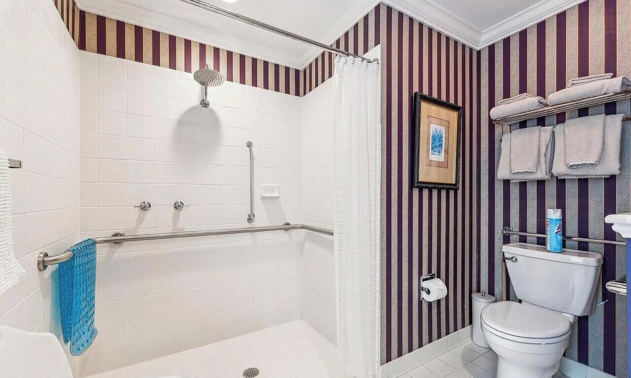 Un baño con bañera, ducha, inodoro y paredes a rayas.