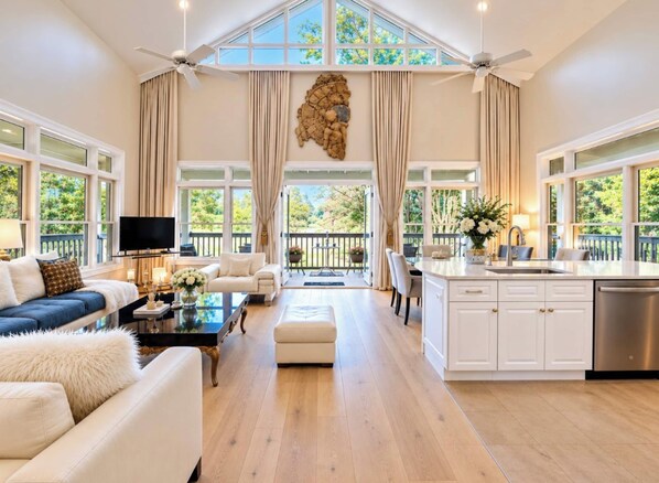 A spacious living room with a large window, a fireplace, and a kitchen area.