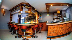Un espace bar avec des tabourets, un comptoir et des étagères remplies de bouteilles et de verres.