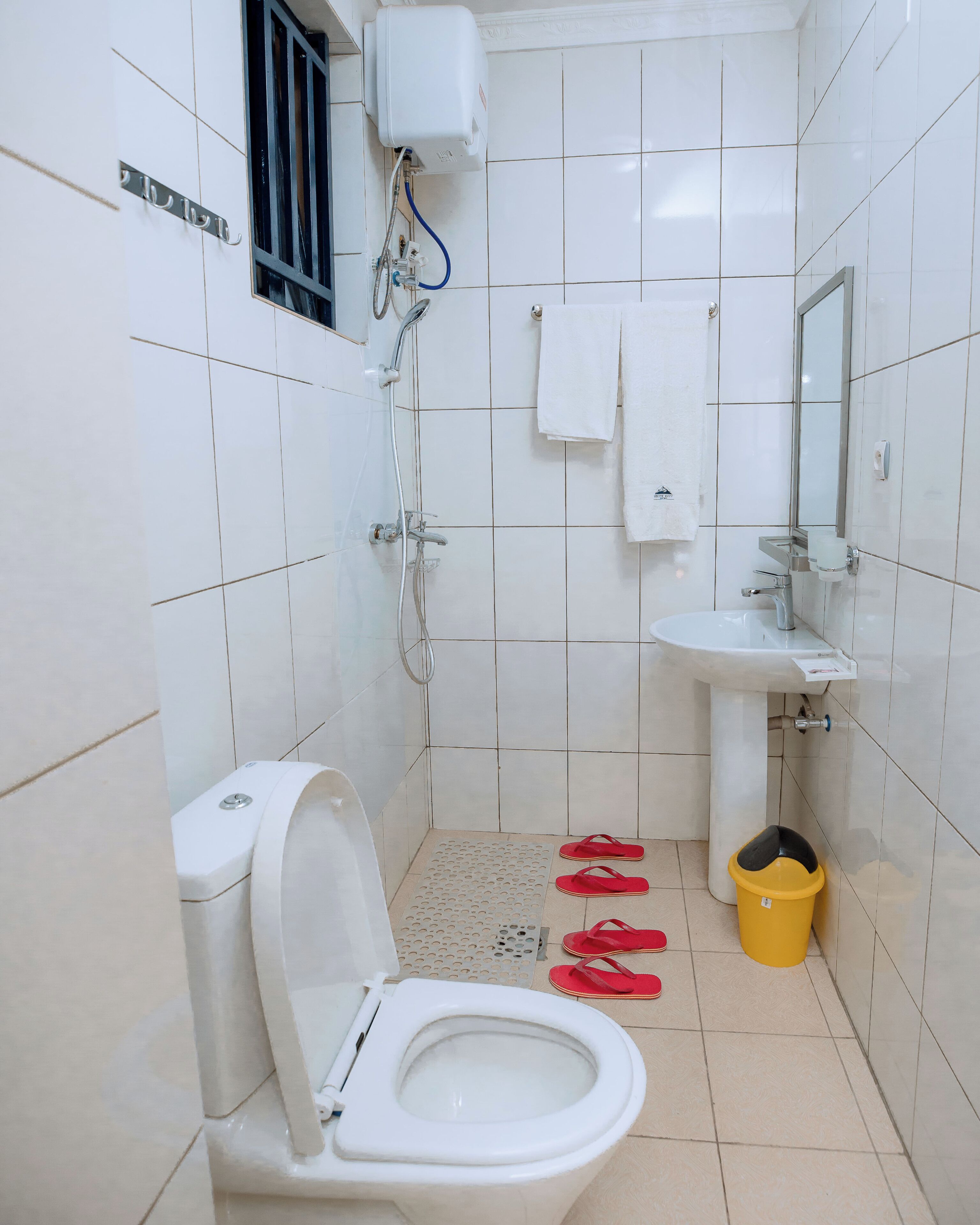 A bathroom with a toilet, sink, mirror, and shower.