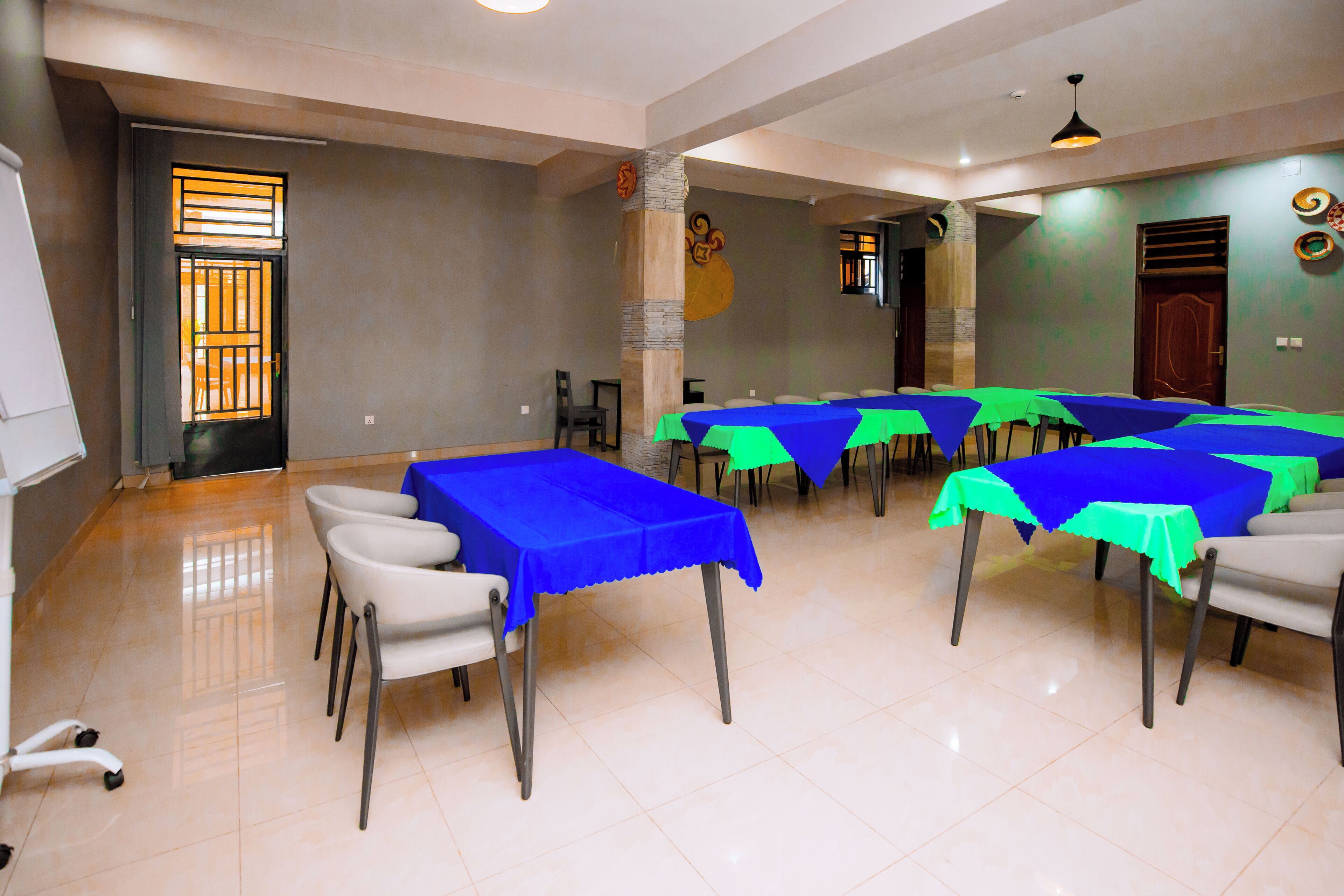 Un salón de conferencias con mesas cubiertas con manteles azules y verdes, dispuestas en forma de U.