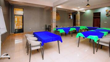 Un salón de conferencias con mesas cubiertas con manteles azules y verdes, dispuestas en forma de U.